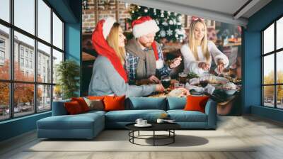 Friends having dinner on Christmas` eve at restaurant. Christmas holidays concept. Wall mural